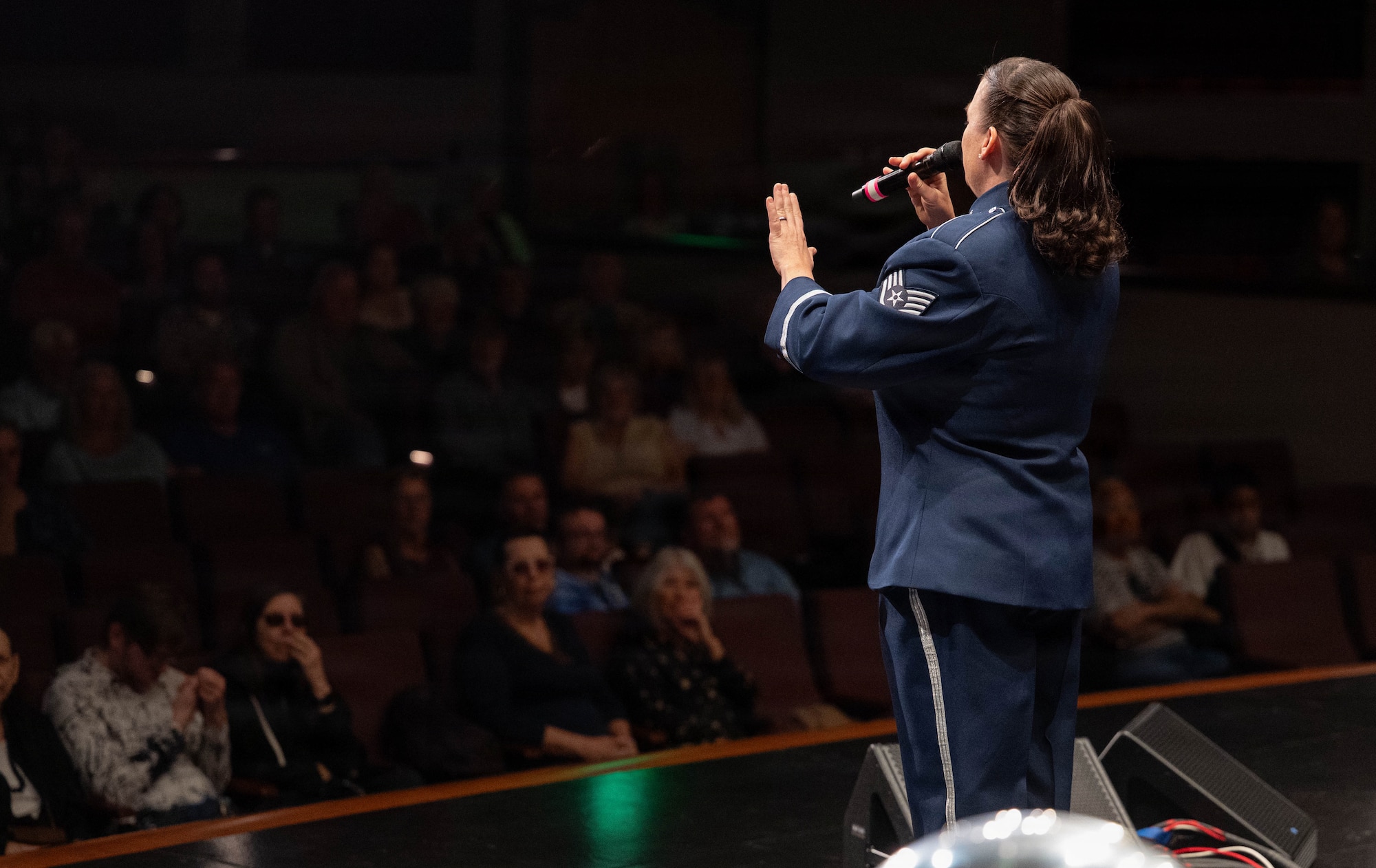 A vocalist sings to a crowd on a stage.