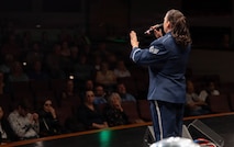 A vocalist sings to a crowd on a stage.