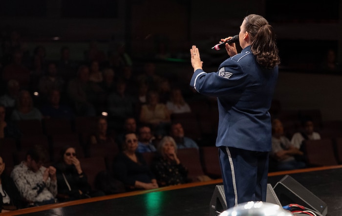 A vocalist sings to a crowd on a stage.