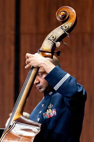 An Airman plays the bass, the neck covers part of his face.