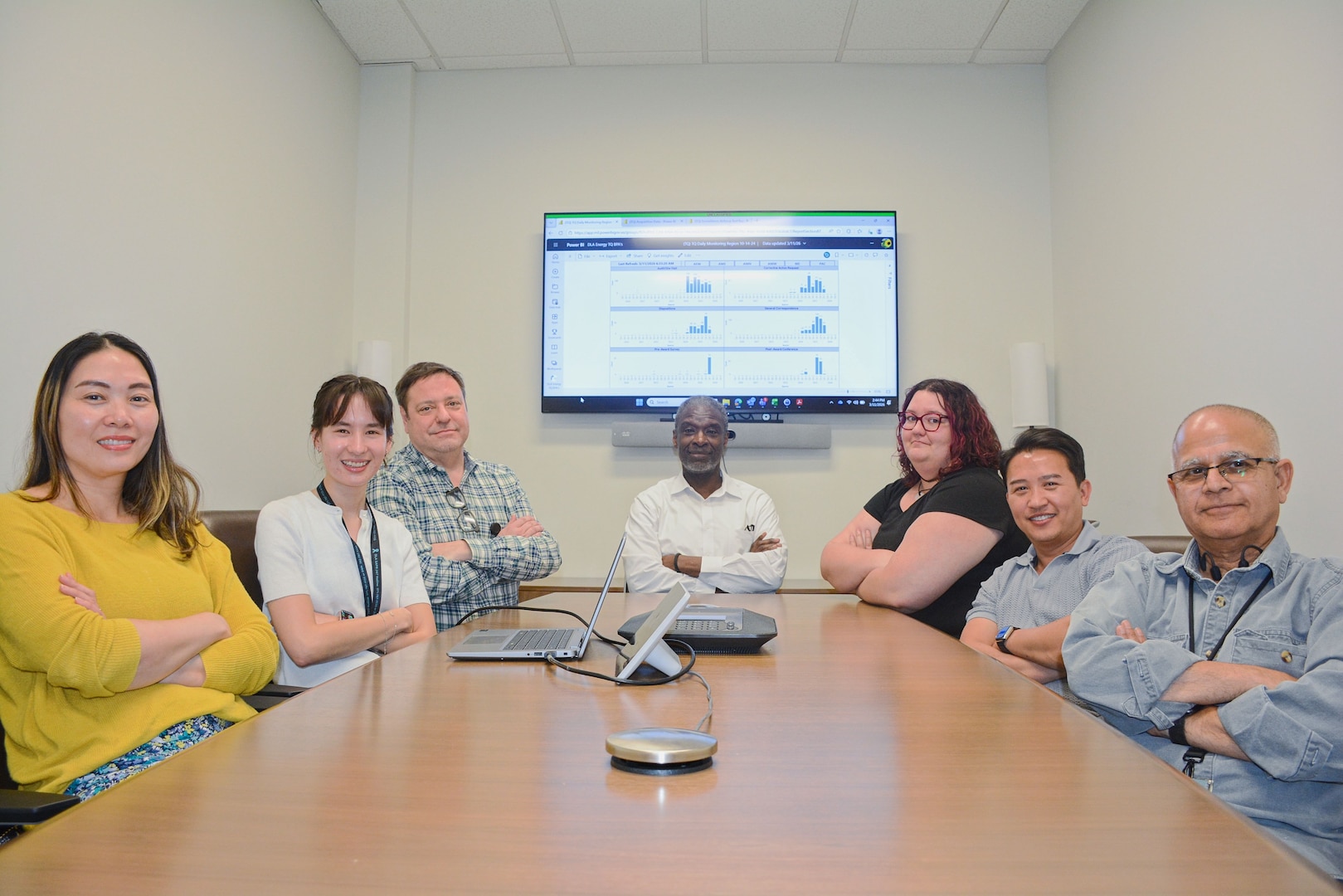 Team of people sit around a desk for a photo op.