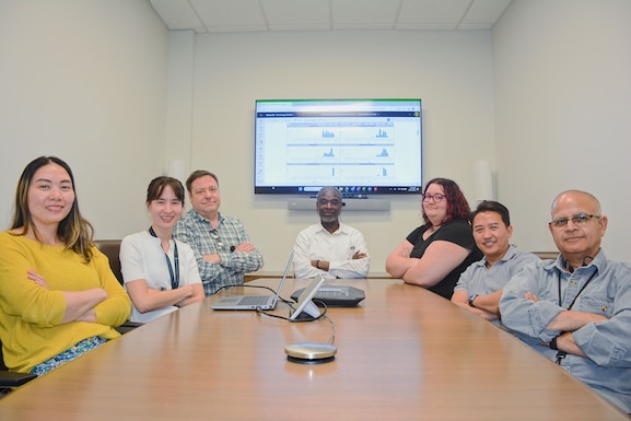 Team of people sit around a desk for a photo op.