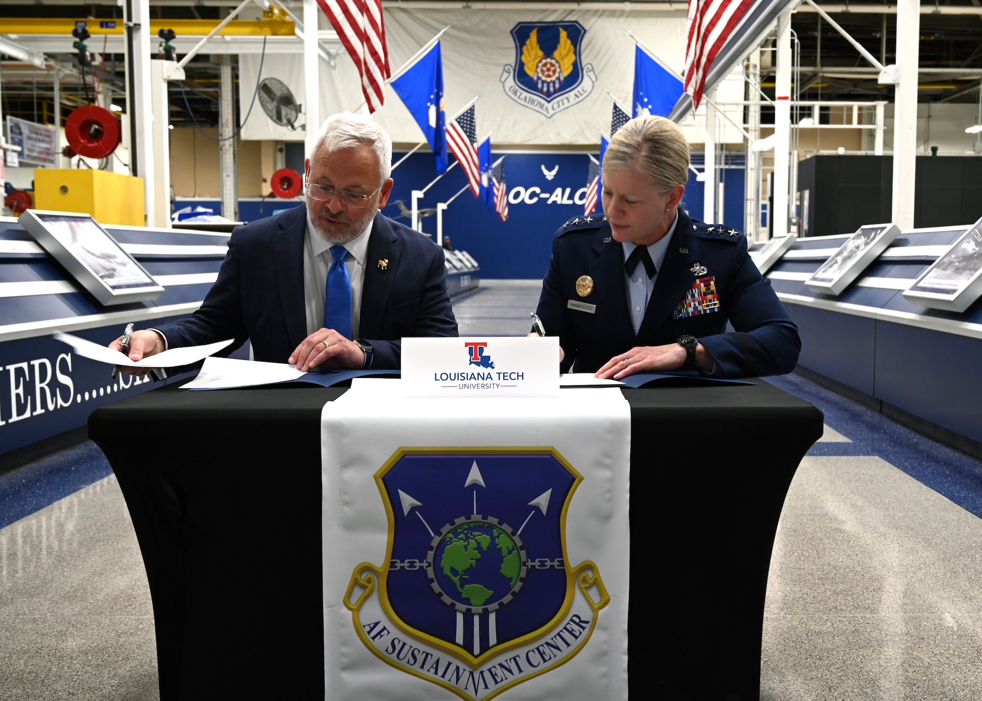 A civilian and military leader signing an agreement.