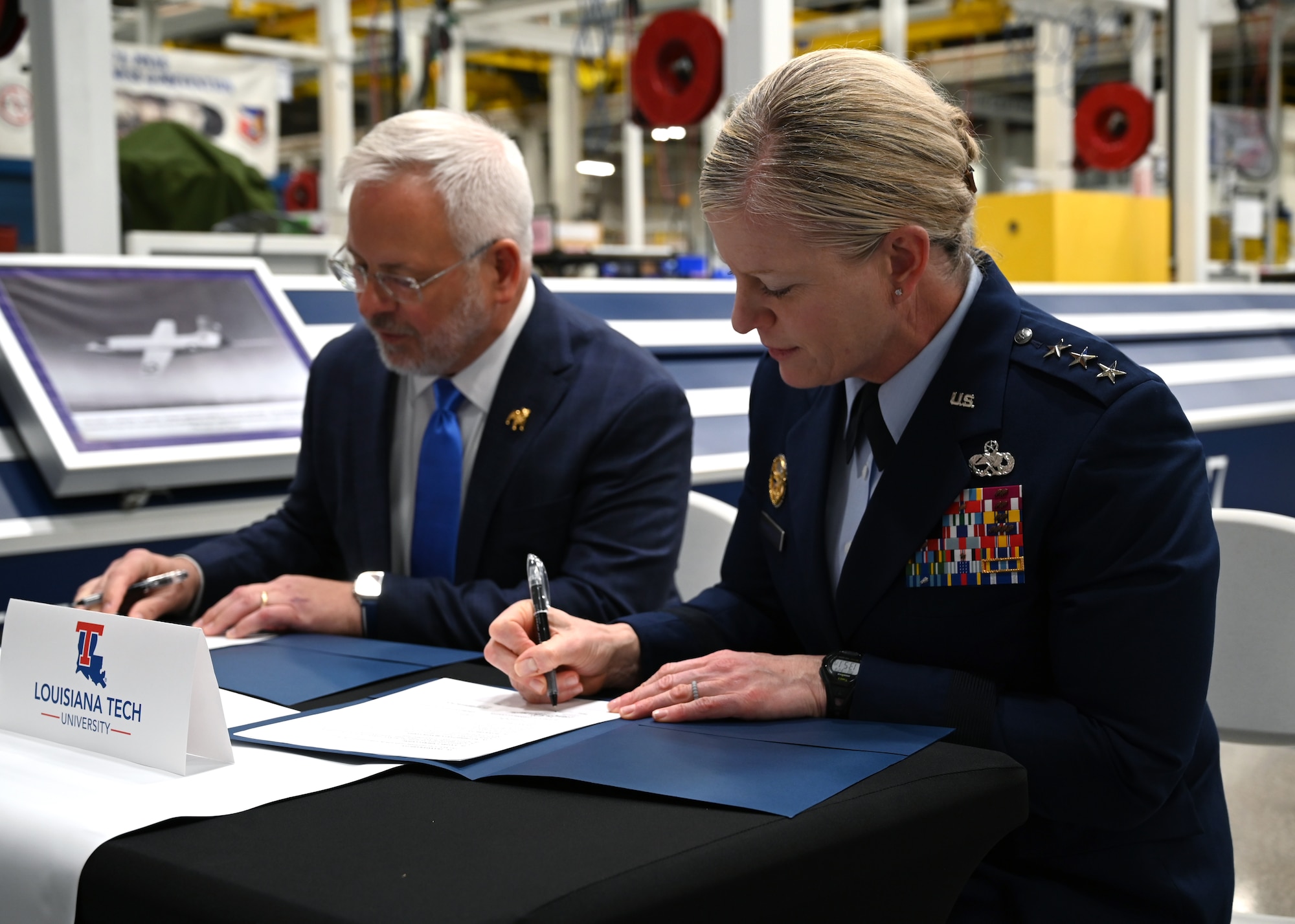 A civilian and military leader signing an agreement.