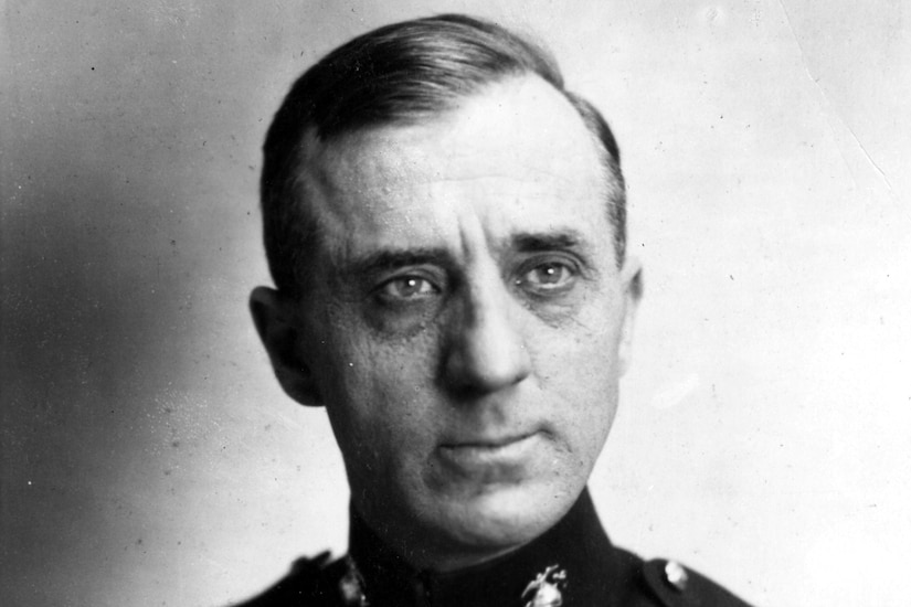 A man in a formal military uniform poses for a portrait.