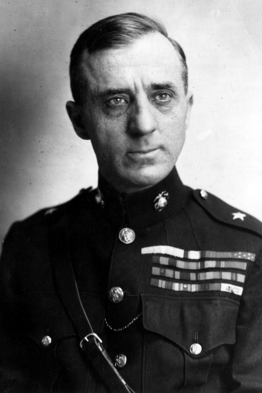 A man in a formal military uniform poses for a portrait.