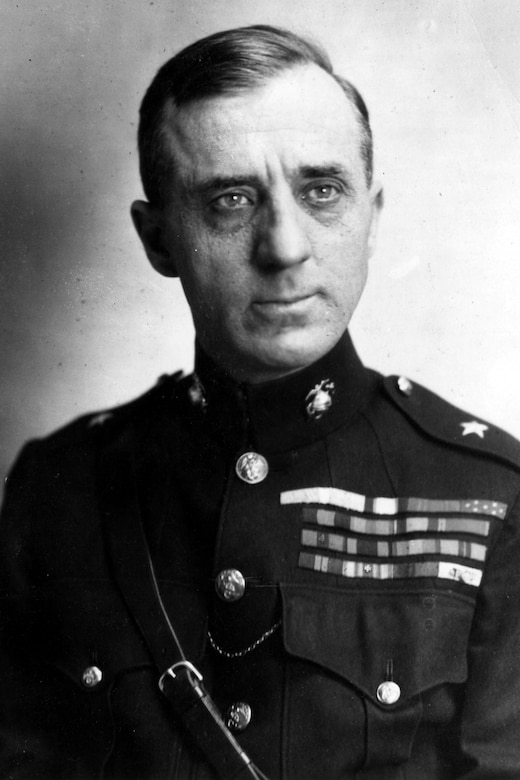 A man in a formal military uniform poses for a portrait.