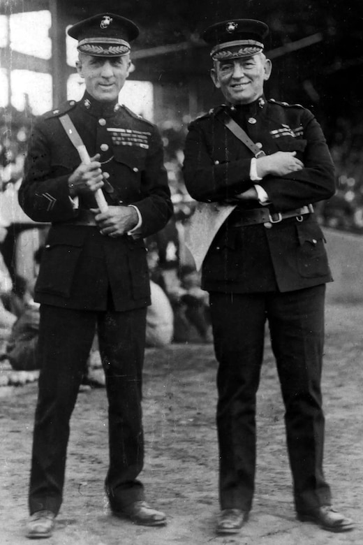 Two men in military dress uniforms smile as they pose for a photo.
