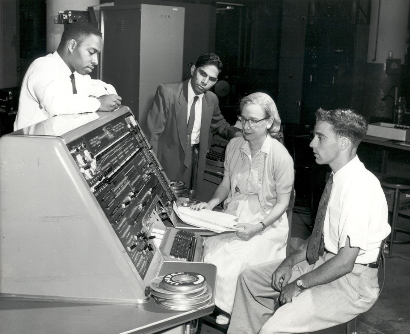 Grace Hopper with three other programmers and the operator's console of the UNIVAC I computer, 1957. Hopper’s work on early computing systems helped advance programming methods that made large-scale, reliable data processing possible across government and defense organizations. (Photo Courtesy of the Computer History Museum)