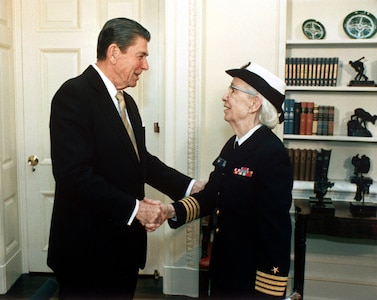 On Dec. 15, 1983, at the White House, President Ronald Reagan congratulates Grace Hopper on her promotion from Captain to Commodore, a title later redesignated as Rear Admiral (Lower Half). Hopper’s decades of service helped shape the Navy’s transition toward standardized, enterprise-scale computing systems. (Photo by Pete Souza, Department of Defense)