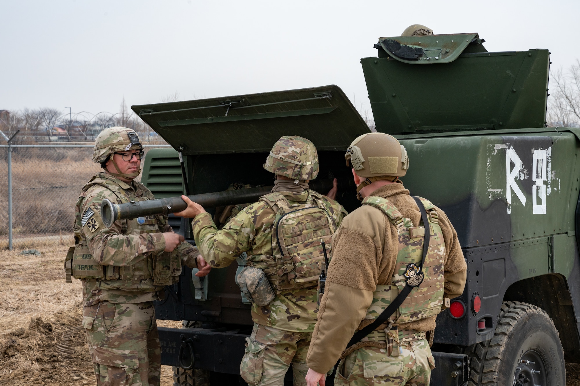 Soldiers load missile launchers into a Humvee.
