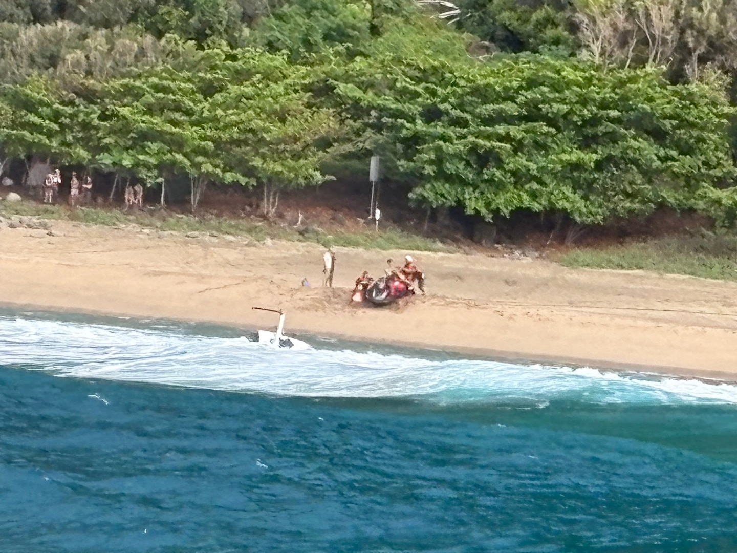 Kauai Ocean Safety members and good Samaritans assist individuals following a helicopter crash on Kalalau Beach on Kauai March 26, 2026. Coast Guard, partner agencies and good Samaritans responded to a helicopter that crash-landed on the sandbar near Kalalau Beach in Kauai. (U.S. Coast Guard photo, courtesy Station Kauai)
