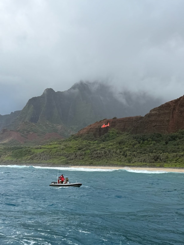A Coast Guard Air Station Barbers Point MH-65 Dolphin helicopter crew and a Kauai Ocean Safety Bureau boat crew traverse the shoreline near Kalalau Beach on Kauai March 26, 2026. The Coast Guard received a report from Kauai Police Dispatch of a helicopter crash-landing near Kalalau Beach with five people aboard. (U.S. Coast Guard photo, courtesy Station Kauai)
