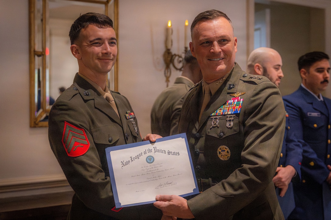 U.S. Marine Corps Lt. Gen. Leonard F. Anderson IV, right, commander of Marine Forces Reserve and Marine Forces South, presents an award to Sgt. Justin Napier, a Marine musician with the Marine Forces Reserve Band, during the military appreciation day luncheon hosted by the New Orleans Navy League at the Metairie Country Club, Metairie, Louisiana, March 18, 2026. The New Orleans Navy League hosted the event to recognize and award service members in the New Orleans area. (U.S. Marine Corps photo by Lance Cpl. Edward Spears)