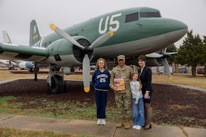 Man, woman and two girls standing in front of C-47 aircraft display