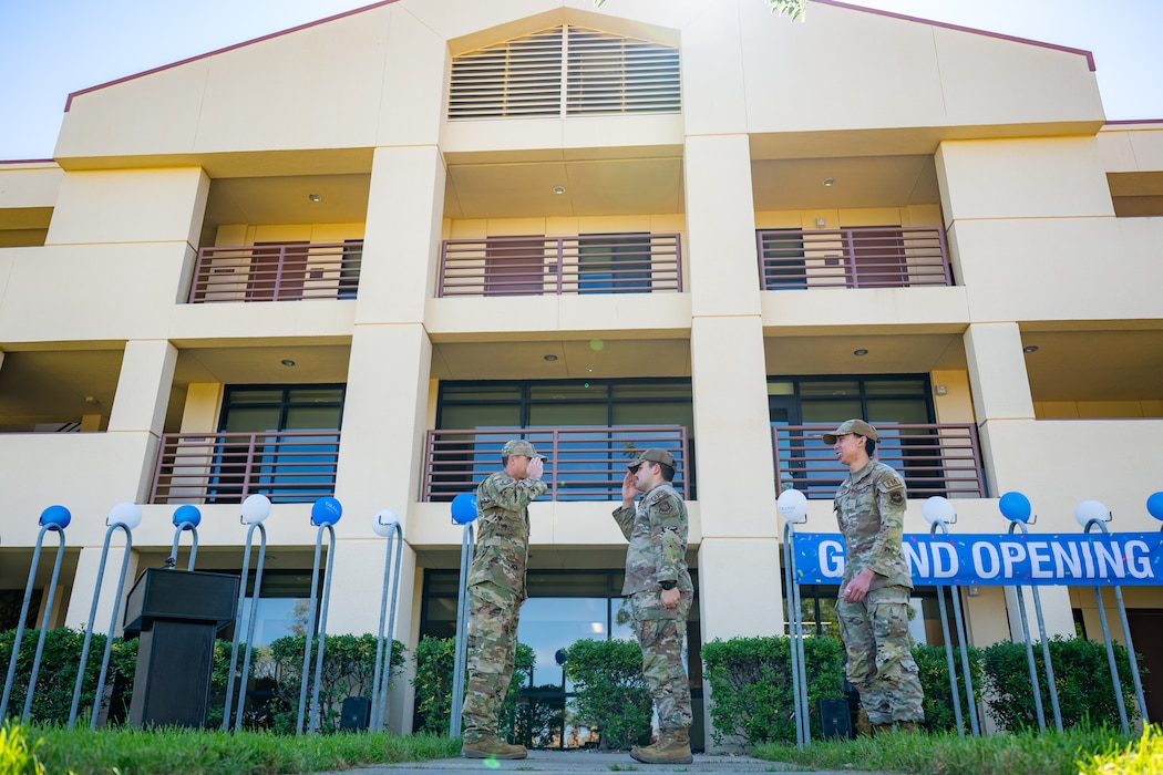Airmen salute eachother in front of a dorm