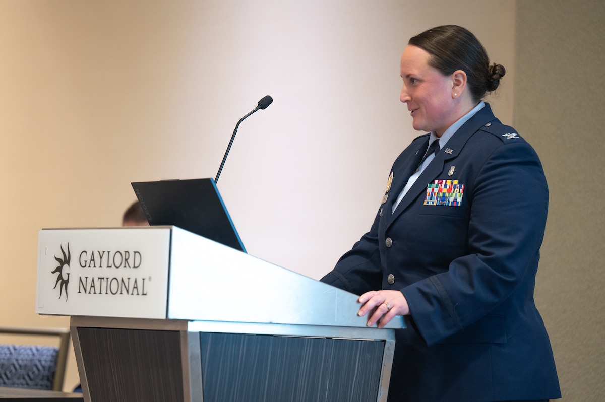 Image of an Airman talking at a podium.