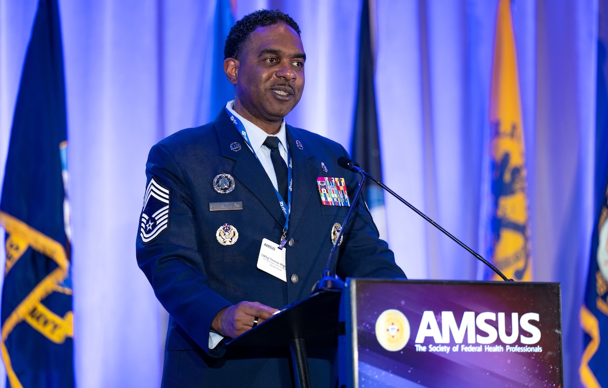 Image of an Airman talking at a podium.