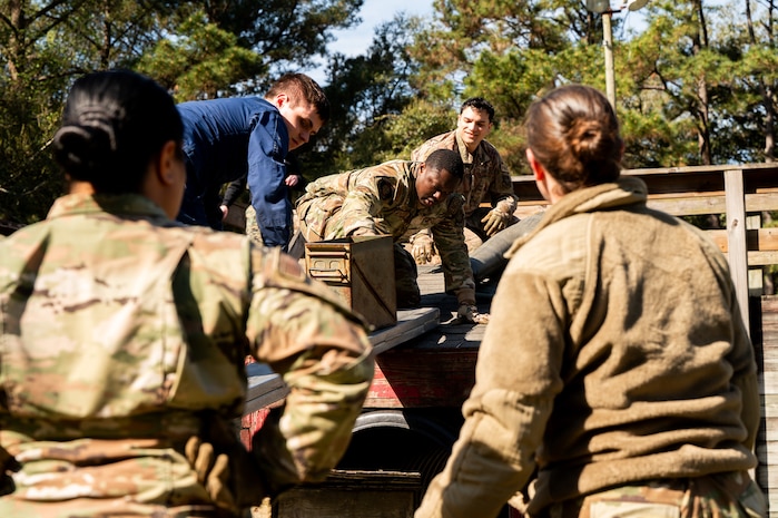 U.S. Airmen work together with a Coastguardsman to move ammo cans during an Airman Leadership School field training exercise at the Marine Corps Recruiting Depot, Parris Island, South Carolina.