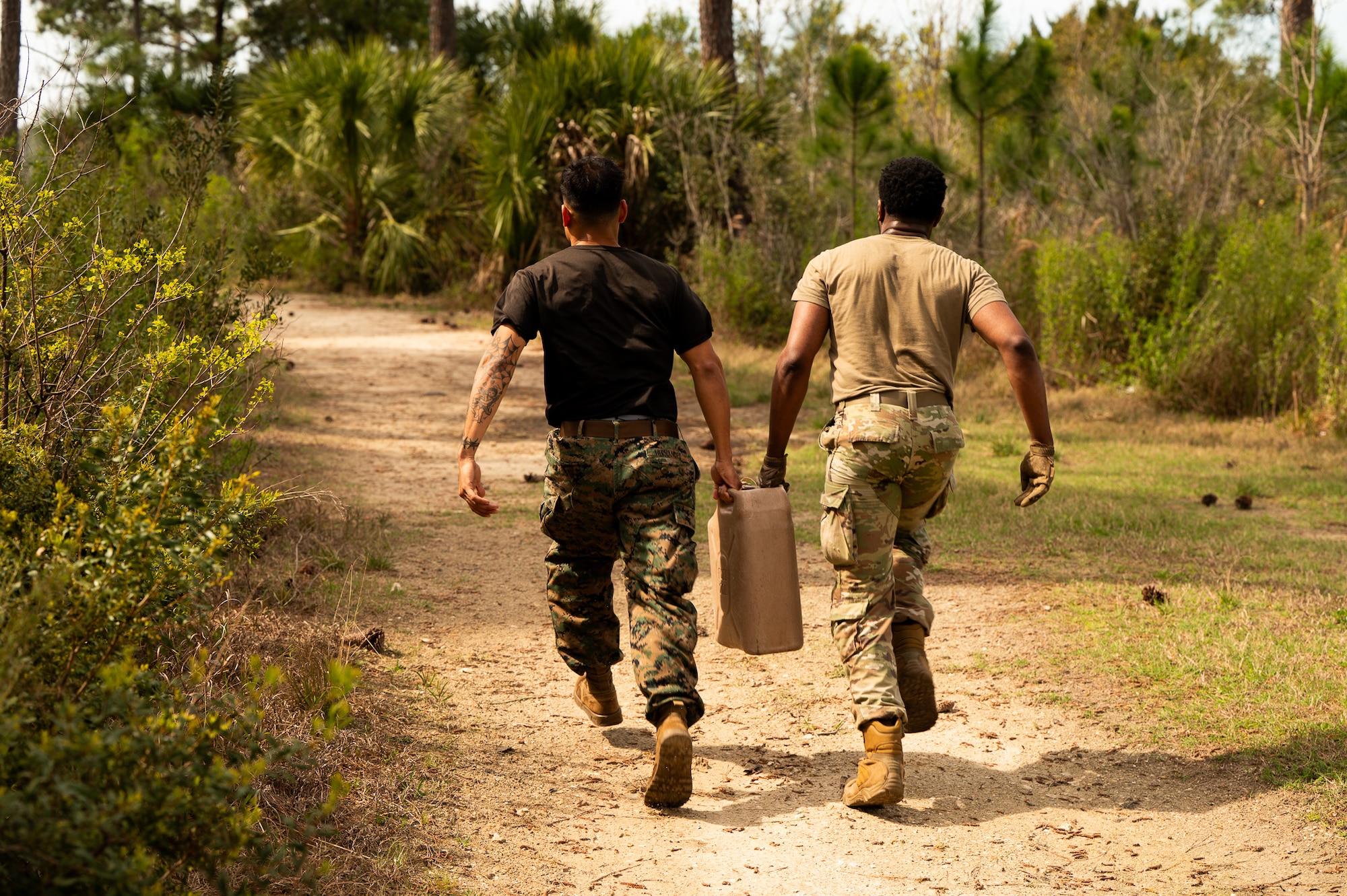 A U.S. Marine and a U.S. Airman carry a gas can while running during the endurance portion of the Airman Leadership School field training exercise at the Marine Corps Recruiting Depot, Parris Island, South Carolina.
