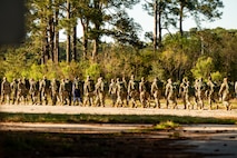 U.S. Marine Corps instructors lead U.S. Airmen and U.S. Coastguardsmen as they march in formation to the first phase of the obstacle course during an Airman Leadership School field training exercise at the Marine Corps Recruiting Depot, Parris Island, South Carolina.