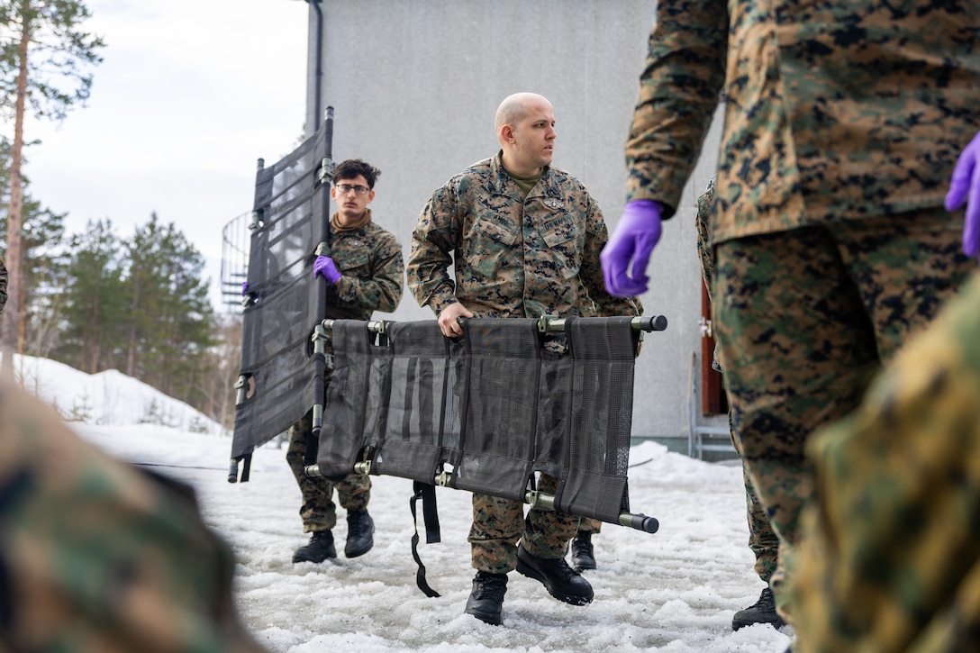 U.S. Navy Hospital Corpsman 3rd Class Dairius Amos, center, and Hospital Corpsman 3rd Class Chinmay Bhatt, both with 2nd Battalion, 6th Marine Regiment, 2nd Marine Division, rush to simulated casualties during a Marine Corps Warfighting Laboratory-led mass casualty drill as part of exercise Cold Response 26 in Setermoen, Norway, March 11, 2026. This drill was held to test medical modernization efforts focused on increasing survivability by pushing advanced care closer to the point of injury. A key component of NATO's enhanced vigilance activity Arctic Sentry, exercise Cold Response 26 is a Norwegian-led winter military exercise designed to enhance collective defense capabilities and ensure U.S. readiness to rapidly deploy and seamlessly operate alongside NATO Allies in challenging arctic conditions. (U.S. Marine Corps photo by Cpl. Michael Bartman)