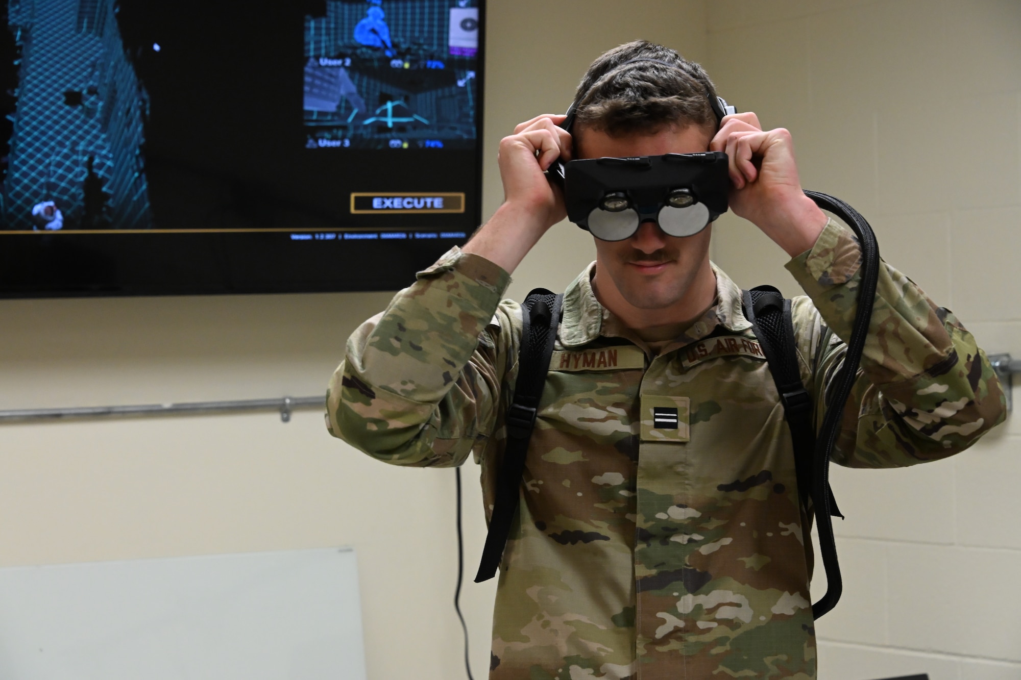 Cadet 1st Lt. Nathan Hyman puts on augmented reality goggles while already wearing the associated backpack.