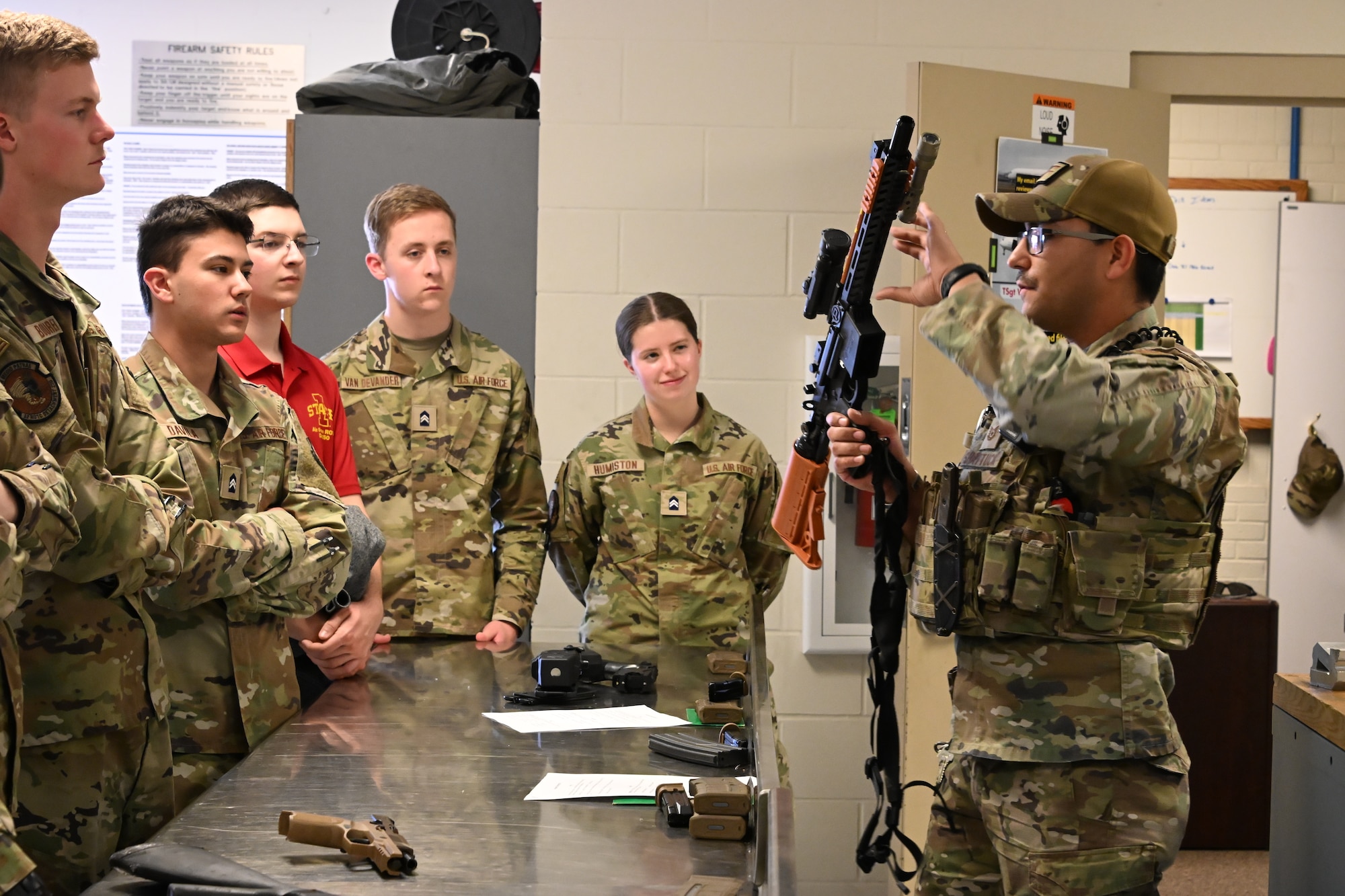 Tech. Sgt. Jakob Shattuck, a 185th Air Refueling Wing Combat Arms Instructor, right, holds up a pepperball launcher as a group of Air Force Reserve Officers’ Training Corps cadets look at him from the left.