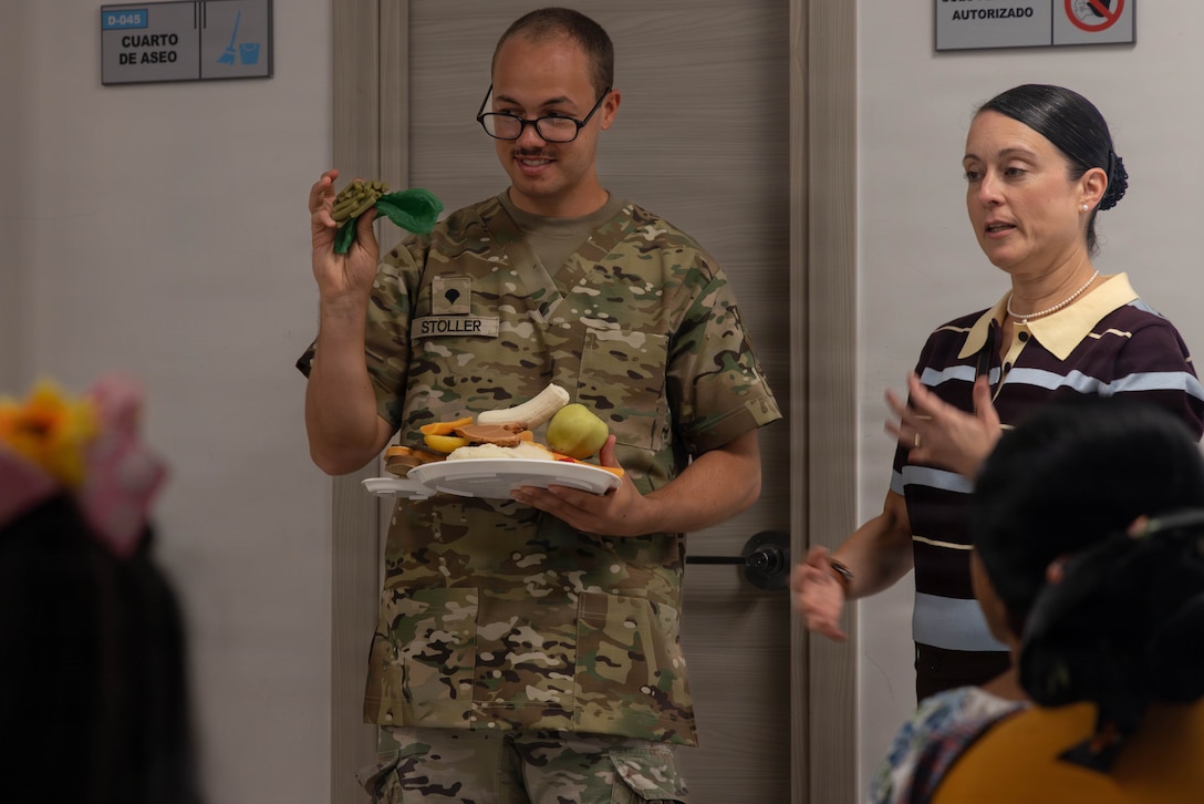 A person in military uniform holds food next to a civilian