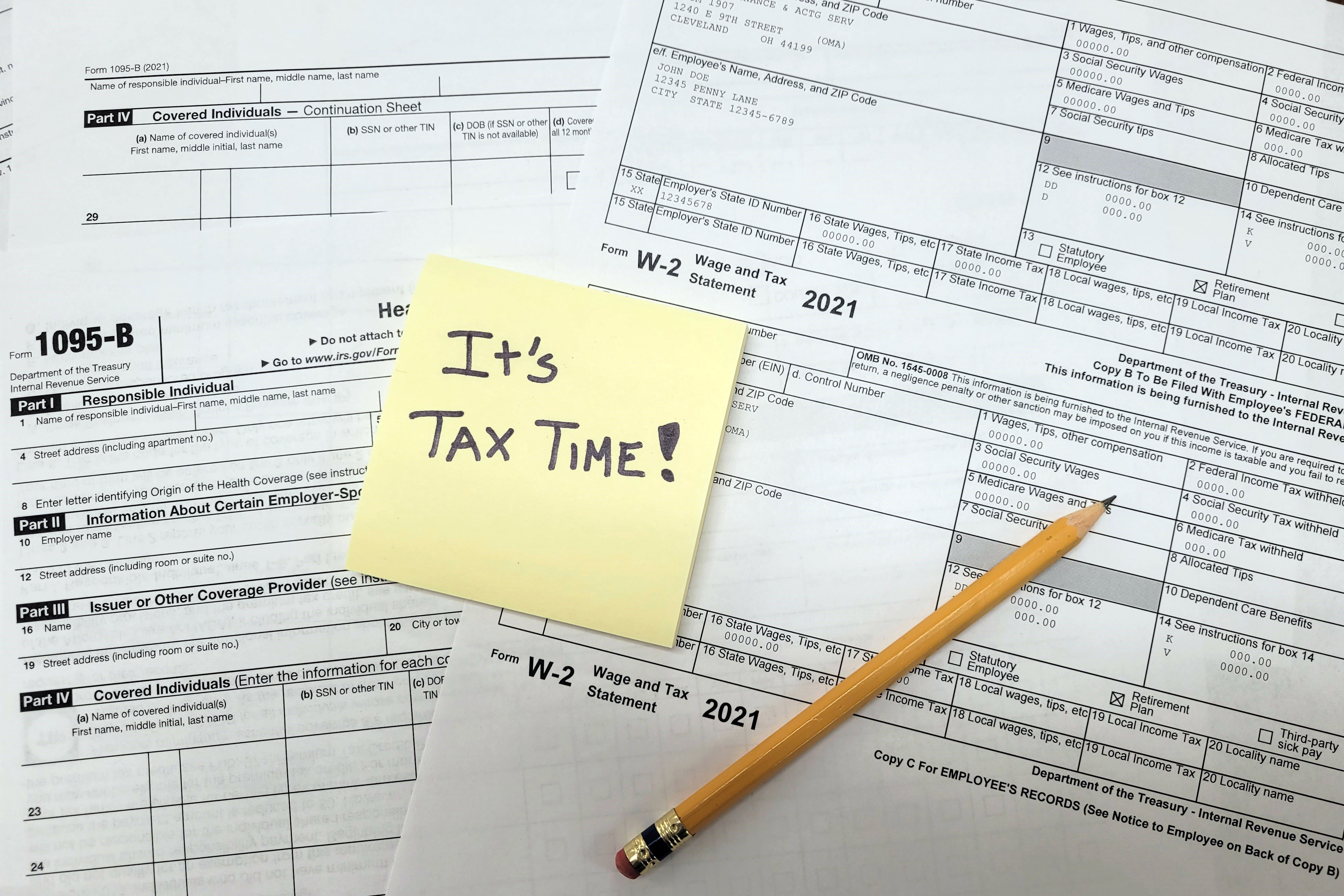 A note reading 'It's tax time!' is posted to a set of tax documents.