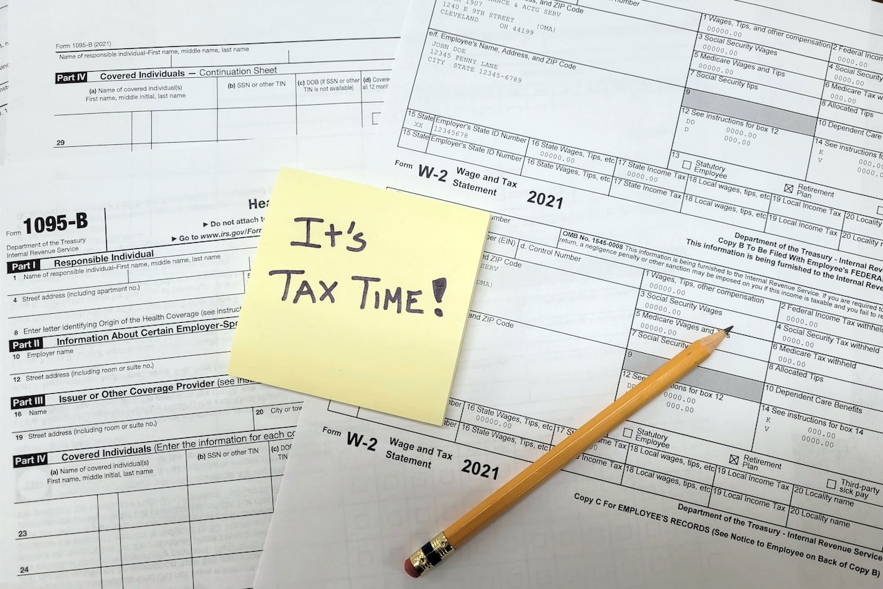 A note reading "It's tax time!" is posted to a set of tax documents.