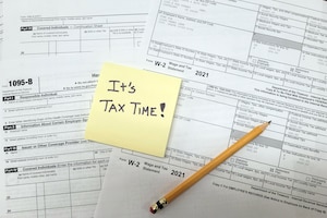 A note reading "It's tax time!" is posted to a set of tax documents.