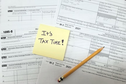 A note reading "It's tax time!" is posted to a set of tax documents.