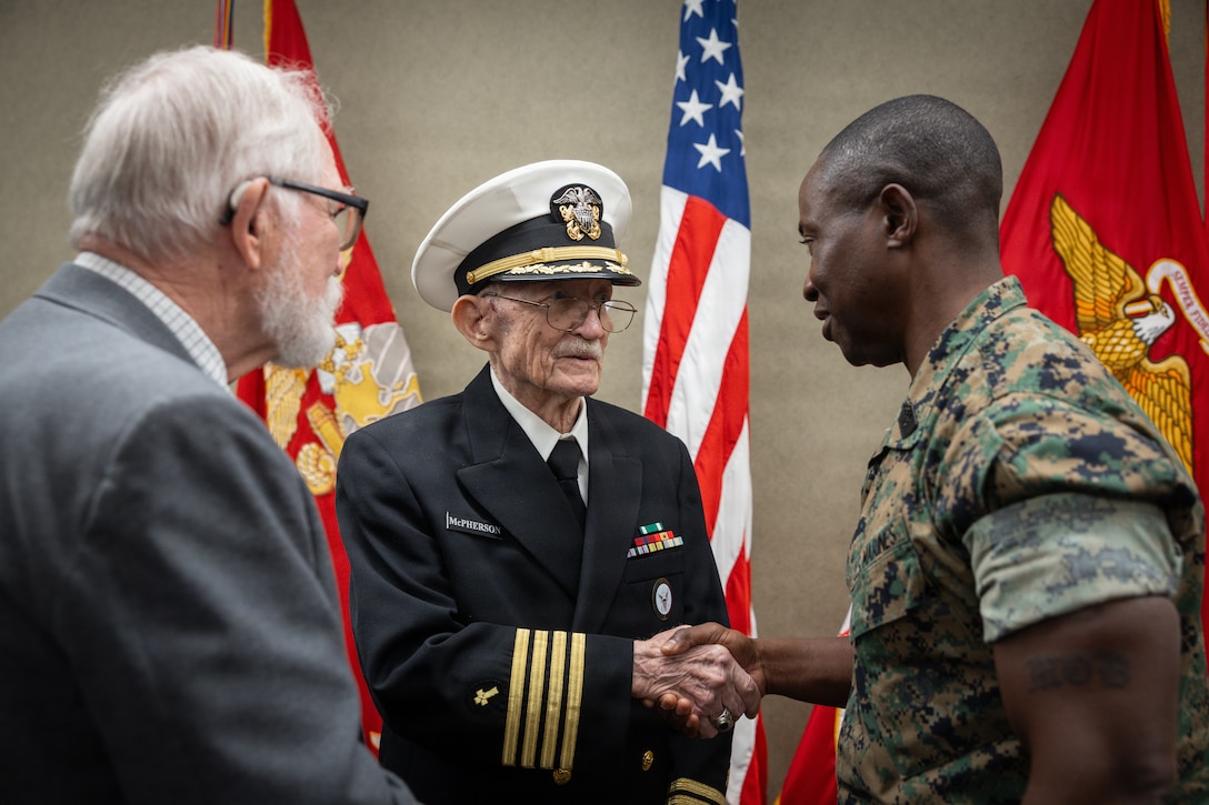 Raymond McPherson, center, brother of the late Maj. Everette McPherson, shakes the hand of U.S. Marine Corps Sgt. Maj. Kabiru M. Labaran, right, senior enlisted leader, Headquarters Battalion, Marine Forces Reserve, before a posthumous Distinguished Flying Cross ceremony honoring the heroic actions of their brother and friend at Marine Support Facility New Orleans, March 18, 2026. The Distinguished Flying Cross is awarded to those who have displayed single acts of heroism or extraordinary achievement while participating in aerial flight. Maj. McPherson, a fighter jet pilot, posthumously received the award for sacrificing his life during the Vietnam War in an attempt to save the life of his co-pilot. (U.S. Marine Corps photo by Lance Cpl. Claire Cheney)