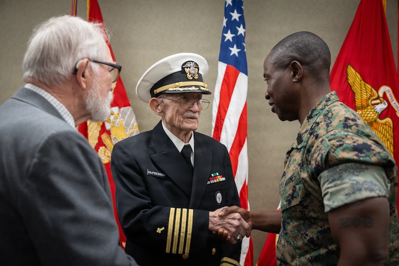 Raymond McPherson, center, brother of the late Maj. Everette McPherson, shakes the hand of U.S. Marine Corps Sgt. Maj. Kabiru M. Labaran, right, senior enlisted leader, Headquarters Battalion, Marine Forces Reserve, before a posthumous Distinguished Flying Cross ceremony honoring the heroic actions of their brother and friend at Marine Support Facility New Orleans, March 18, 2026. The Distinguished Flying Cross is awarded to those who have displayed single acts of heroism or extraordinary achievement while participating in aerial flight. Maj. McPherson, a fighter jet pilot, posthumously received the award for sacrificing his life during the Vietnam War in an attempt to save the life of his co-pilot. (U.S. Marine Corps photo by Lance Cpl. Claire Cheney)