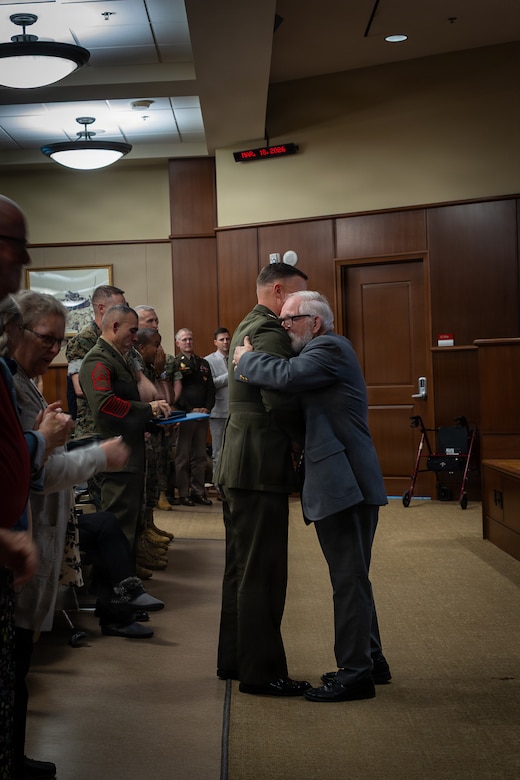 Allan McPherson, right, brother of the late Maj. Everette McPherson, hugs U.S. Marine Corps Lt. Gen. Leonard F. Anderson IV, left, commander of Marine Forces Reserve and Marine Forces South during a posthumous Distinguished Flying Cross ceremony honoring the heroic actions of his brother at Marine Support Facility New Orleans, March 18, 2026. The Distinguished Flying Cross is awarded to those who have displayed single acts of heroism or extraordinary achievement while participating in aerial flight. Maj. McPherson, a fighter jet pilot, posthumously received the award for sacrificing his life during the Vietnam War in an attempt to save the life of his co-pilot.  (U.S. Marine Corps photo by Lance Cpl. Claire Cheney)