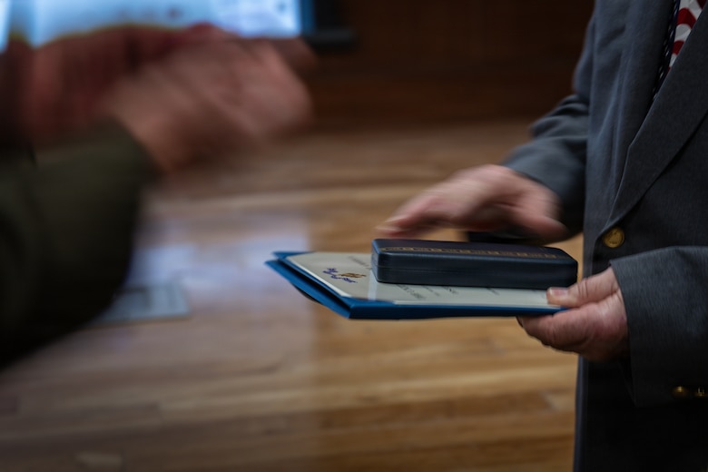 Allan McPherson, brother of the late Maj. Everette McPherson, is presented a certificate and medal during a posthumous Distinguished Flying Cross ceremony honoring the heroic actions of his brother at Marine Support Facility New Orleans, March 18, 2026. The Distinguished Flying Cross is awarded to those who have displayed single acts of heroism or extraordinary achievement while participating in aerial flight. Maj. McPherson, a fighter jet pilot, posthumously received the award for sacrificing his life during the Vietnam War in an attempt to save the life of his co-pilot. (U.S. Marine Corps photo by Lance Cpl. Claire Cheney)