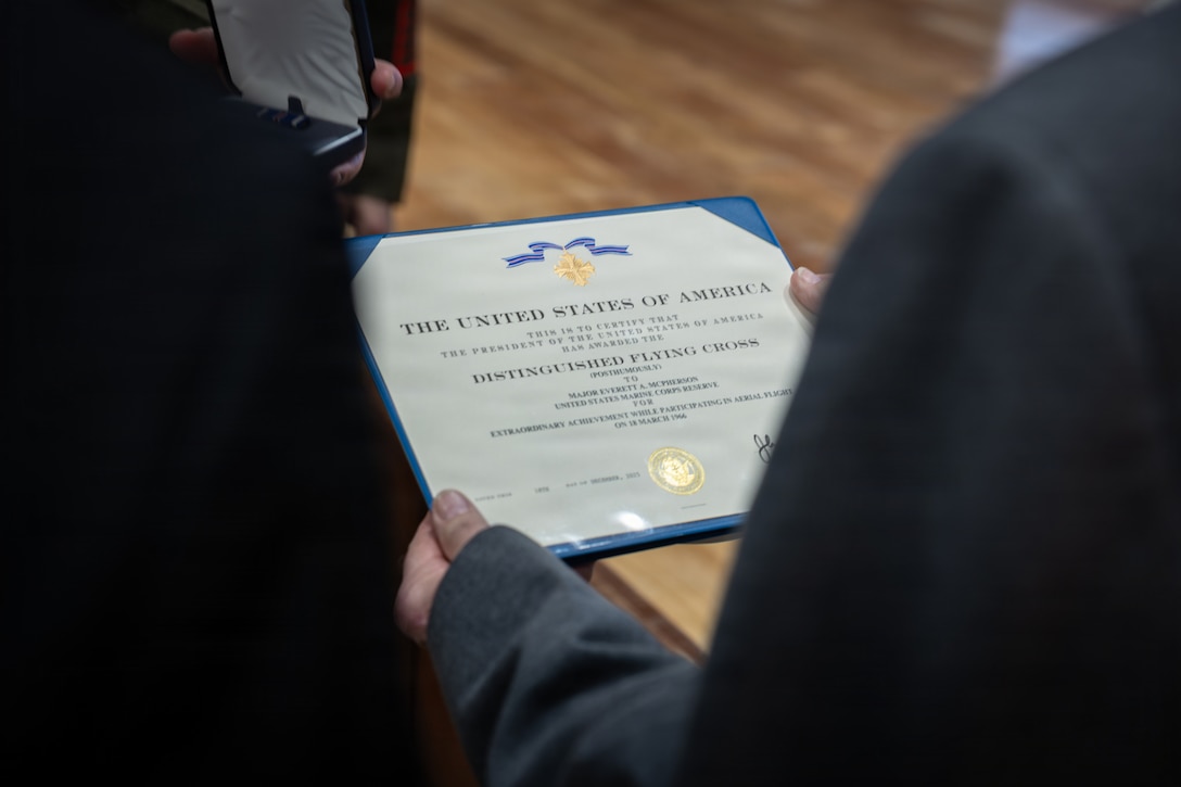 Allan McPherson, brother of the late Maj. Everette McPherson, holds a certificate during a posthumous Distinguished Flying Cross ceremony honoring the heroic actions of this brother at Marine Support Facility New Orleans, March 18, 2026. The Distinguished Flying Cross is awarded to those who have displayed single acts of heroism or extraordinary achievement while participating in aerial flight. Maj. McPherson, a fighter jet pilot, posthumously received the award for sacrificing his life during the Vietnam War in an attempt to save the life of his co-pilot. (U.S. Marine Corps photo by Lance Cpl. Claire Cheney)