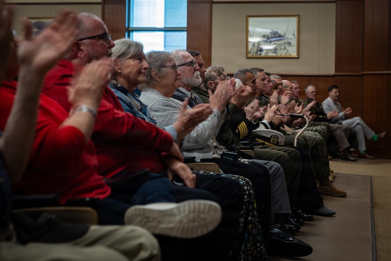 Family and friends of the late Maj. Everette McPherson, applaud during a posthumous Distinguished Flying Cross ceremony honoring the heroic actions of their loved one at Marine Support Facility New Orleans, March 18, 2026. The Distinguished Flying Cross is awarded to those who have displayed single acts of heroism or extraordinary achievement while participating in aerial flight. Maj. McPherson, a fighter jet pilot, posthumously received the award for sacrificing his life during the Vietnam War in an attempt to save the life of his co-pilot. (U.S. Marine Corps photo by Lance Cpl. Claire Cheney)
