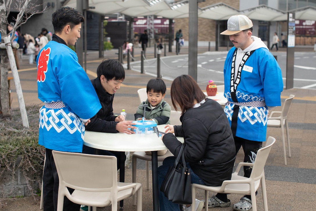 Aviation Support Equipment Technician 2nd Class Tye Showalter with Aircraft Intermediate Maintenance Department (AIMD) Iwakuni and community members play a board game together during Plat ABC's 4-year anniversary celebration in Iwakuni, Japan, March 22, 2026. Plat ABC is a local cafe in Iwakuni city that provides an opportunity for cultural and language exchange for members of the Iwakuni community. (U.S. Marine Corps photo by Lance Cpl. Tyler Bassett)