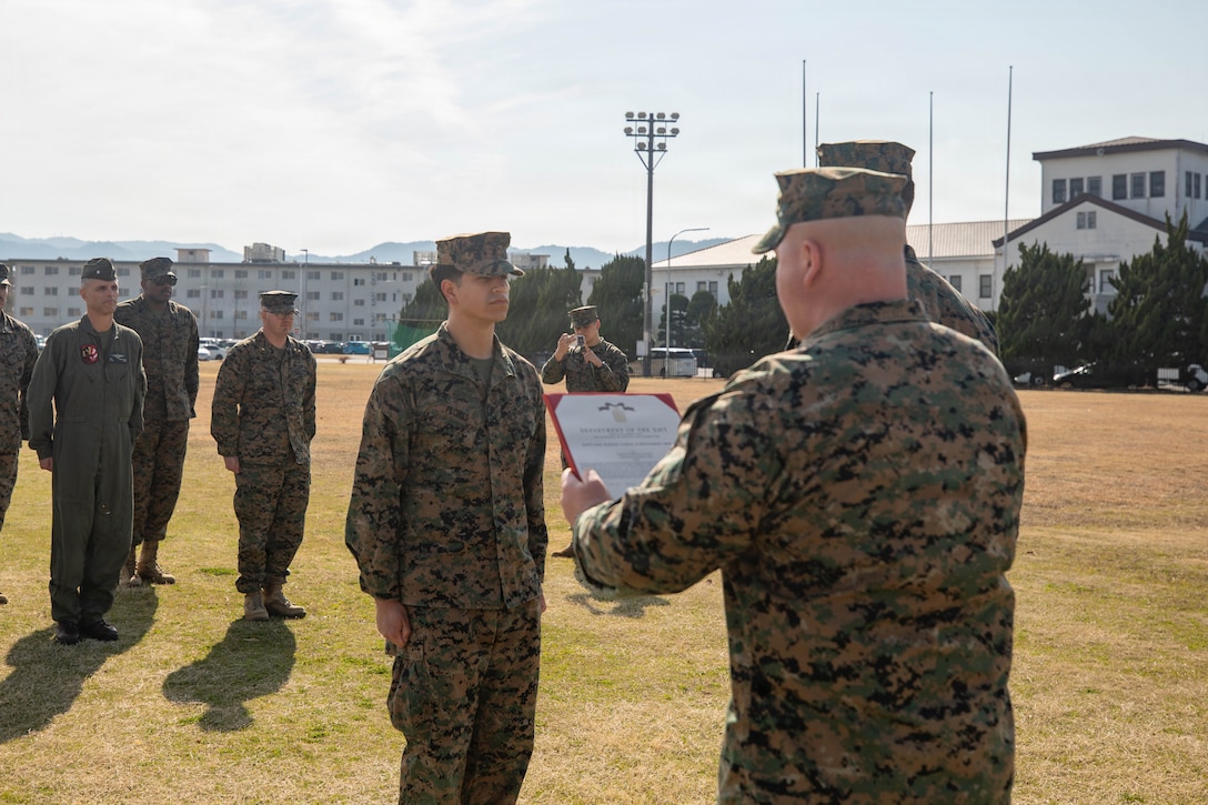 U.S. Marine Corps Staff Sgt. Joseph Leitsch, right, a career planner with Headquarters and Headquarters Squadron (HHS), Marine Corps Air Station Iwakuni, and a native of Pittsburgh, Pennsylvania, reads a Navy and Marine Corps Achievement Medal citation for Sgt. Christian Flores, a career planner with HHS, MCAS Iwakuni, and a native of Sharon, Wisconsin, during an award ceremony at MCAS Iwakuni, Japan, March 17, 2026. Sgt. Flores received a NAM for his performance as a career planner over the past 6 years. (U.S. Marine Corps photo by Lance Cpl. Tyler Bassett)