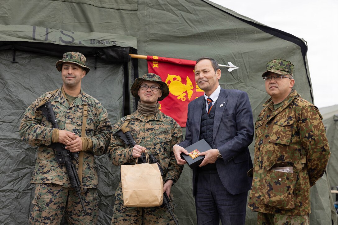 From left to right, U.S. Marine Corps Gunnery Sgt. Kevin Pelaez, senior enlisted advisor of Combat Logistics Company 36, Combat Logistics Regiment 35, 3rd Marine Logistics Group, and a Florida native; 1st Lt. Joel Dorman, company commander of CLC-36, CLR-35, 3rd MLG, and a Pennsylvania native; Oku Masachika, the mayor of Nagi; and Japan Ground Self-Defense Force Lt. Col. Hidekatsu Kamiya, commander of the Training Ground Management Office, JGSDF Camp Nihonbara, pose for a group photo after a base camp tour during exercise Northern Dragon 26 at JGSDF Camp Nihonbara, Okayama, Japan, March 15, 2026. CLC-36 holds exercise Northern Dragon yearly to enhance and maintain the unit’s logistics capabilities, combat marksmanship proficiency, and medical preparedness in austere terrain and weather conditions. (U.S. Marine Corps photo by Cpl. Colin Thibault)