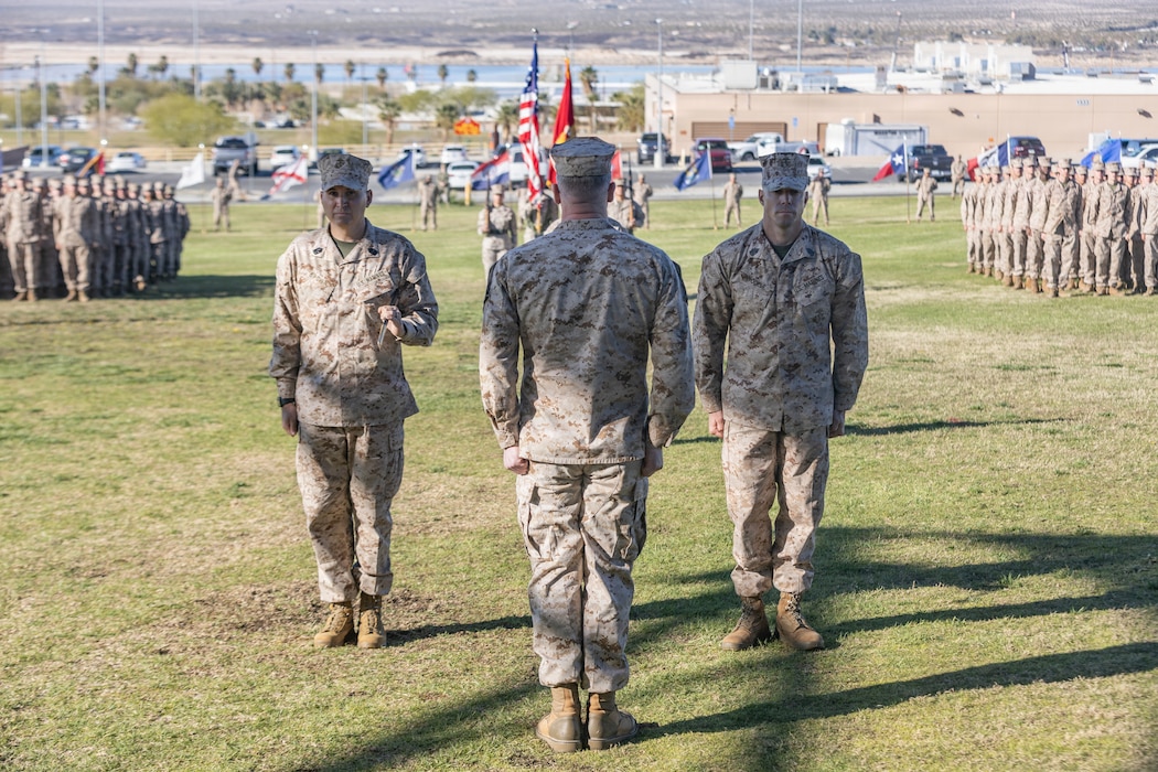 U.S. Marine Corps Sgt. Maj. Mitchell Brown, left, an Alabama native, outgoing senior enlisted leader for Air Control Training Squadron, Marine Corps Communication-Electronics School, and Sgt. Maj. Keane Wodele, right, a Minnesota native, incoming senior enlisted leader for ACTS, MCCES, prepare to pass the noncommissioned Officer sword with Lt. Col. Knathan LeFever, commanding officer of ACTS, MCCES, during the relief and appointment ceremony for ACTS at Lance Cpl. Torrey L. Gray Field, Marine Corps Air Ground Combat Center, Twentynine Palms, California, March 12, 2026. The ceremony marked the official transfer of authority from Sgt. Maj. Mitchell Brown to Sgt. Maj. Keane Wodele. (U.S. Marine Corps photo by Lance Cpl. Cody Fitzgerald)