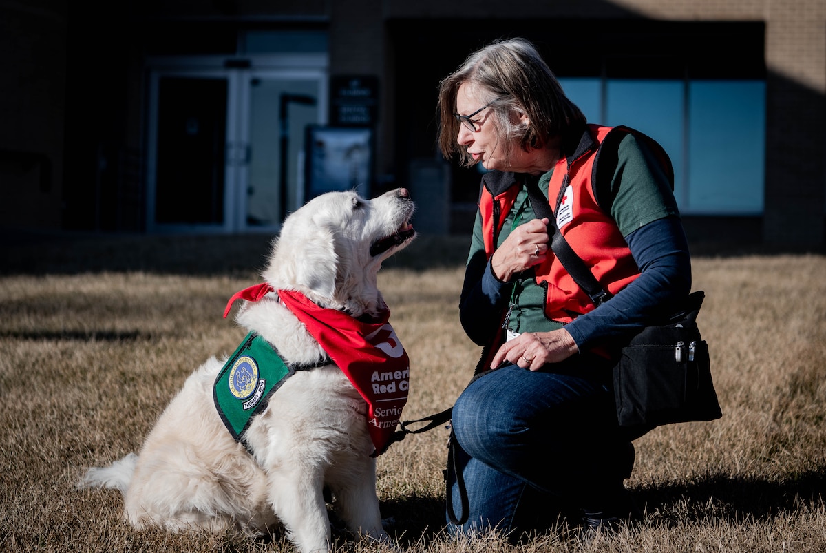 Sharon Hall, American Red Cross volunteer and therapy dog handler, sits outside the 55th Medical Group's Ehrling Berquist clinic with her therapy dog, Izy, in Bellevue, Nebraska, Feb. 13, 2026. Hall and Izy visit different medical facilities to provide support to patients, medical staff and visitors. (U.S. Air Force photo by Daniel Martinez)