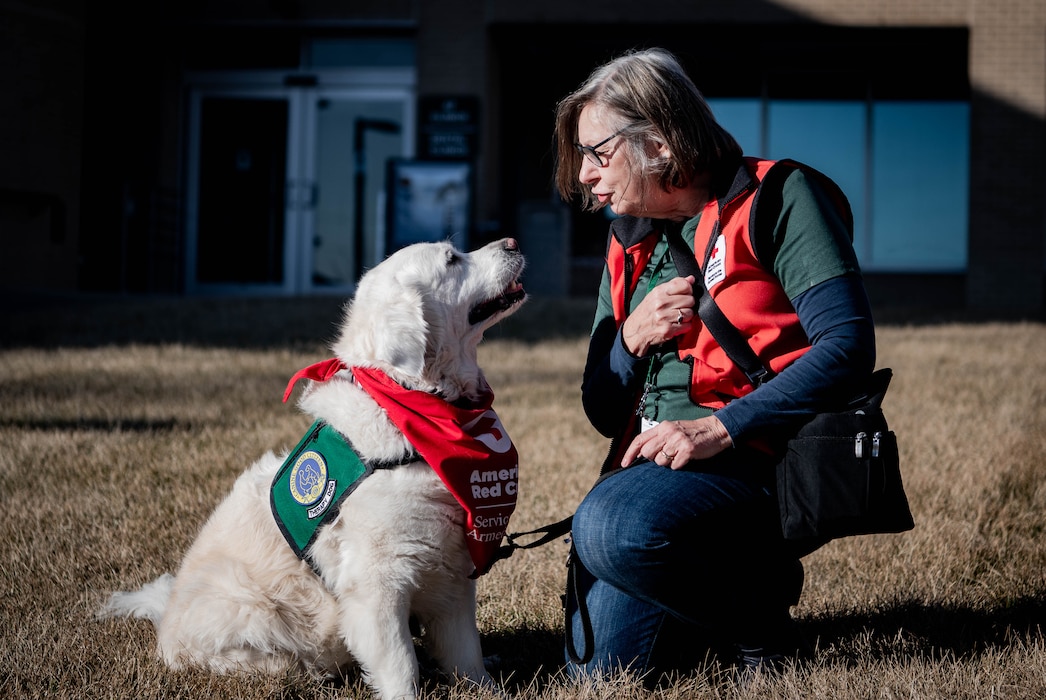 Sharon Hall, American Red Cross volunteer and therapy dog handler, sits outside the 55th Medical Group's Ehrling Berquist clinic with her therapy dog, Izy, in Bellevue, Nebraska, Feb. 13, 2026. Hall and Izy visit different medical facilities to provide support to patients, medical staff and visitors. (U.S. Air Force photo by Daniel Martinez)
