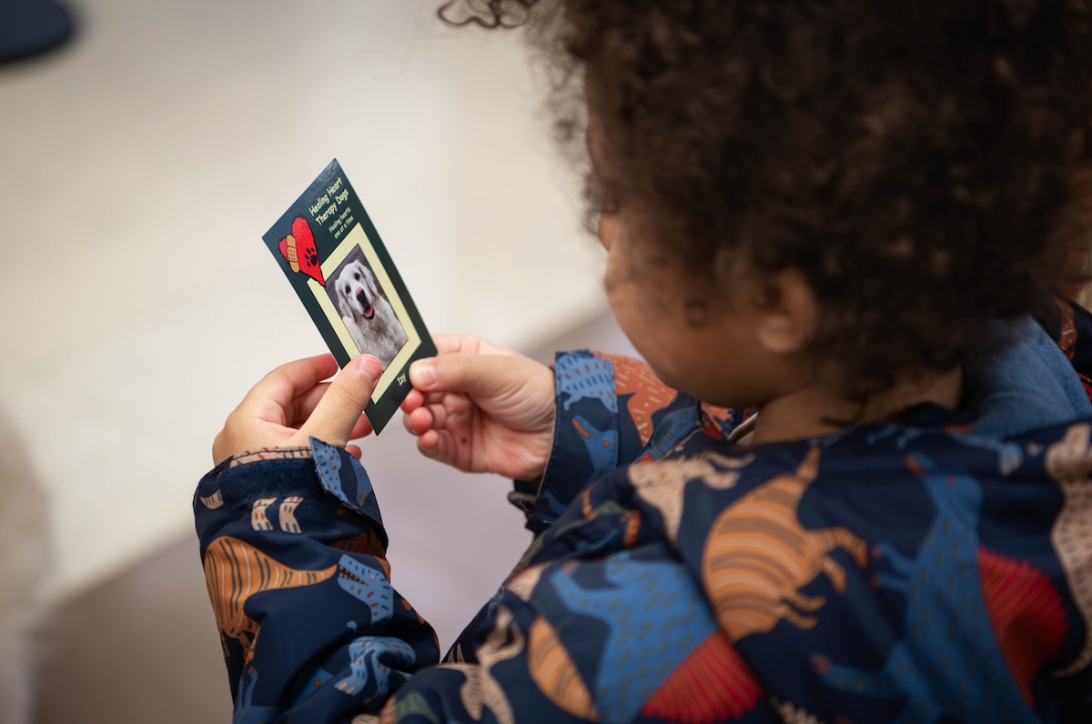 Julius, son of Staff Sgt. Kevin Spencer, 55th Maintenance Squadron aerospace ground equipment, holds a card featuring therapy dog, Izy, while at the 55th Medical Group's Ehrling Bergquist clinic in Bellevue, Neb., Feb. 13, 2026. Sharon Hall, American Red Cross volunteer, therapy dog handler and Izy's owner, will sometimes give cards of Izy to children visiting the clinic as a keepsake. (U.S. Air Force photo by Daniel Martinez)