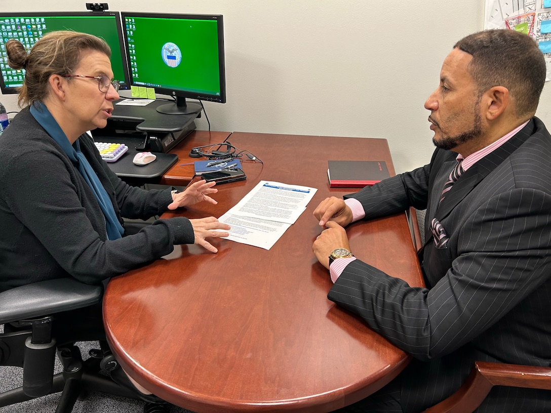 Two people have a desk side discussion.