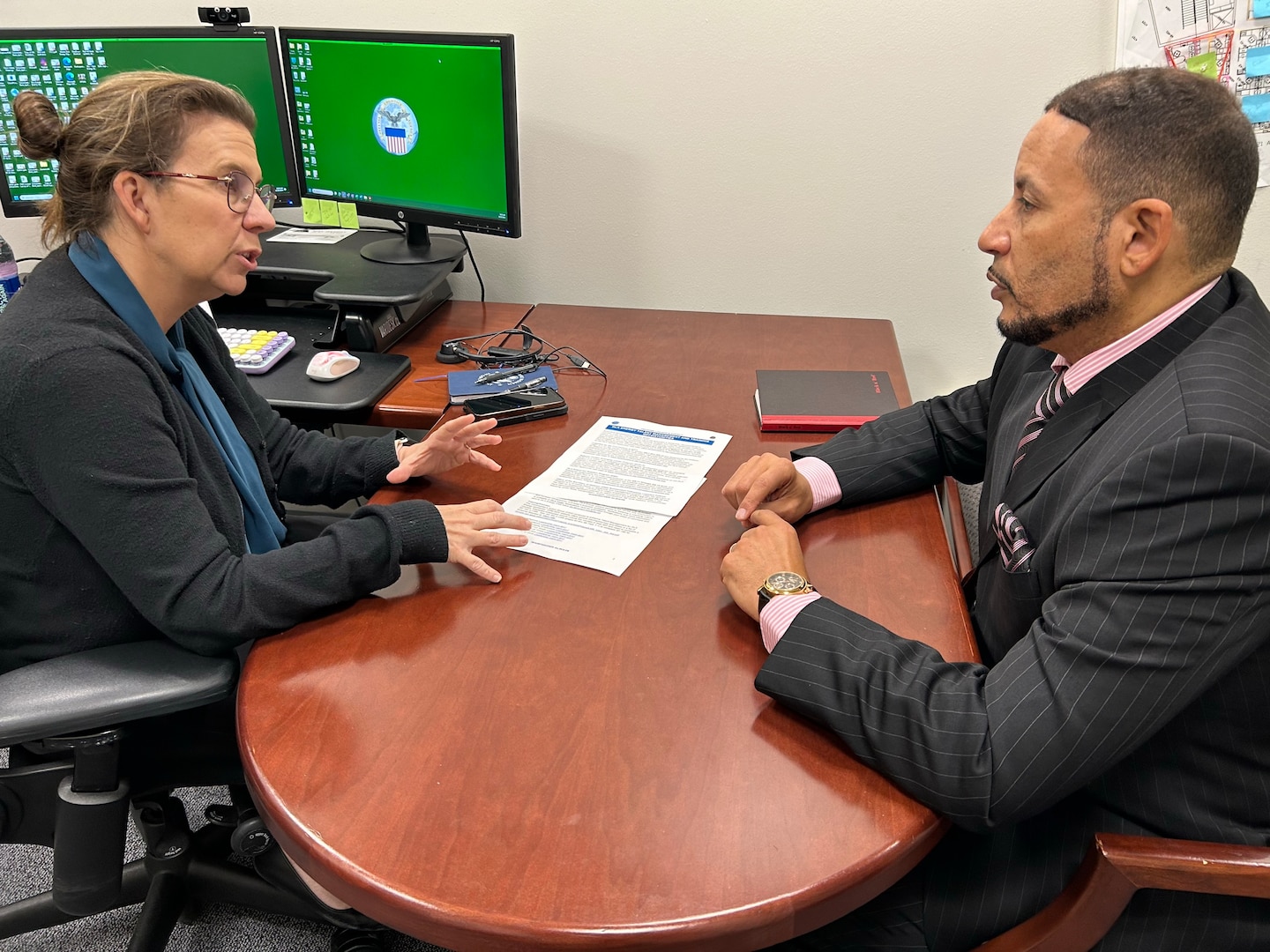 Two people have a desk side discussion.