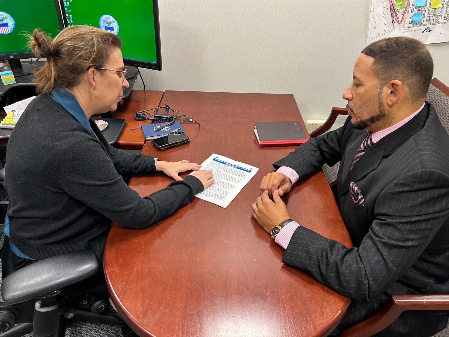 Two people have a desk side discussion.