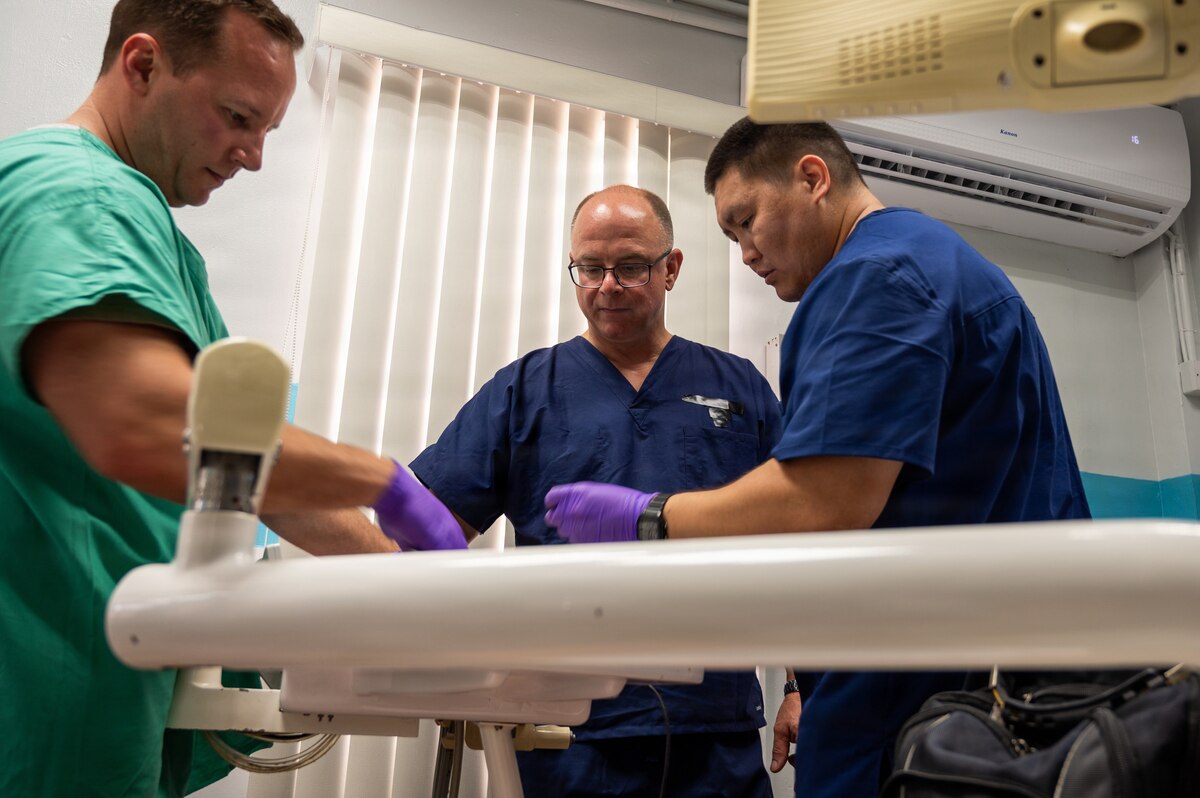 U.S. Air Force Tech. Sgt. Jonathan Rousseau, left, Master Sgt. Matthew Chouinard, and Staff Sgt. Emilbek Dzhoumakeev, all biomedical equipment technicians (BMET) assigned to the 920th Aeromedical Staging Squadron, repair a dental unit waterline on a dental table at the Cheddi Jagan Dental School in Georgetown, Guyana, March 19, 2026. The Lesser Antilles Medical Assistance Team 2026 mission enabled U.S. Air Force BMET professionals to strengthen their technical readiness while working alongside local partners to improve equipment reliability and foster enduring partnerships. (U.S. Air Force photo by Maj. Stephani Schafer)